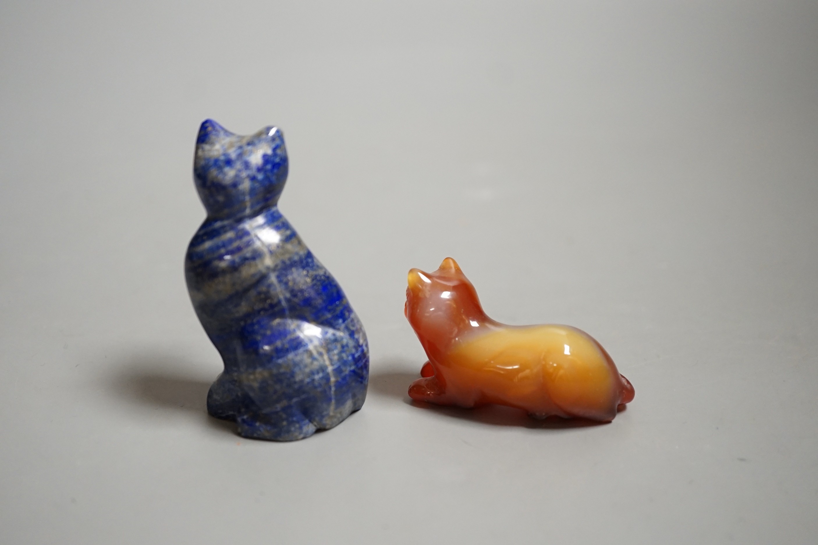 A Chinese carved lapis lazuli seated cat, a banded agate recumbent cat on hardwood stand and a white metal mounted agate scent bottle